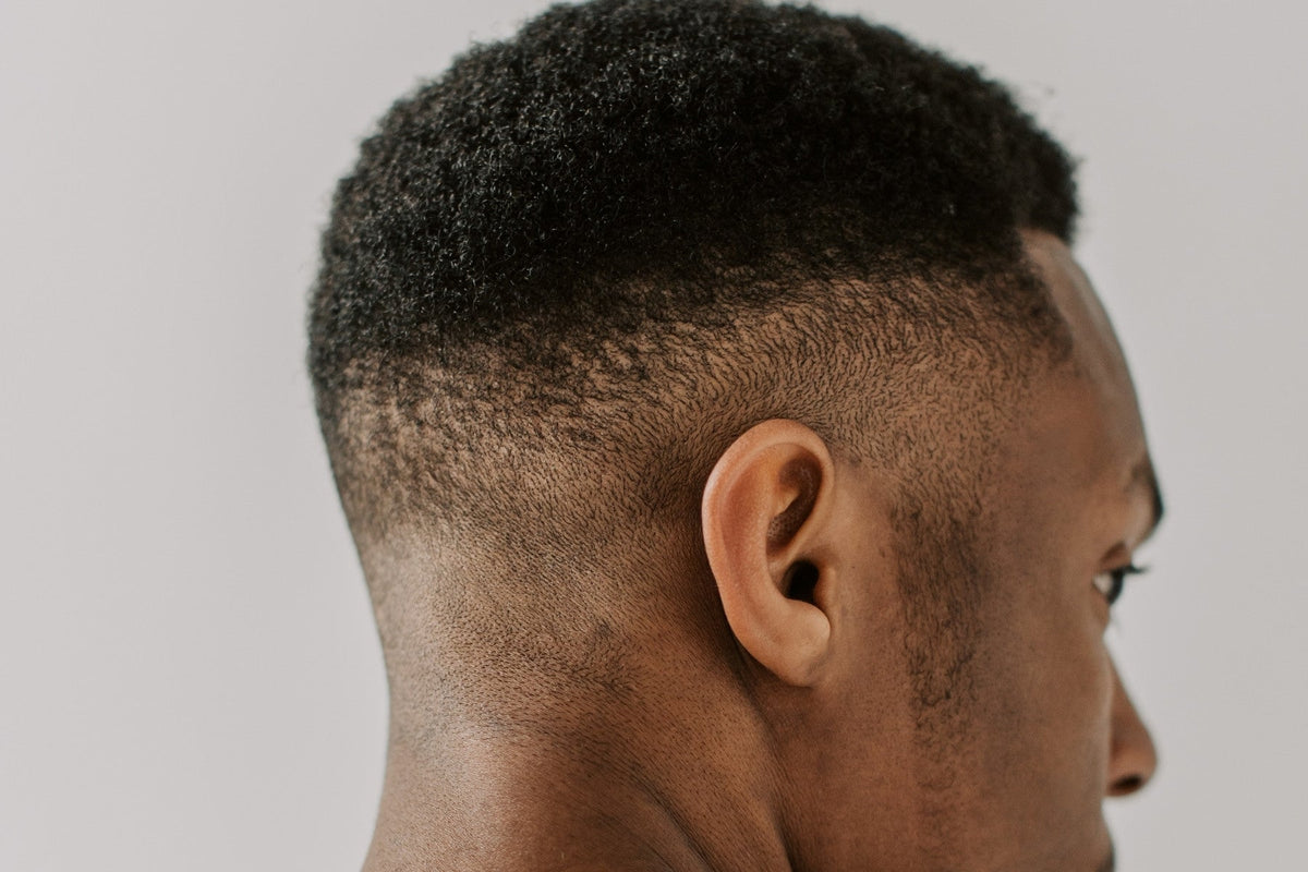 Back of a man's head with a close fade haircut, soft grey light